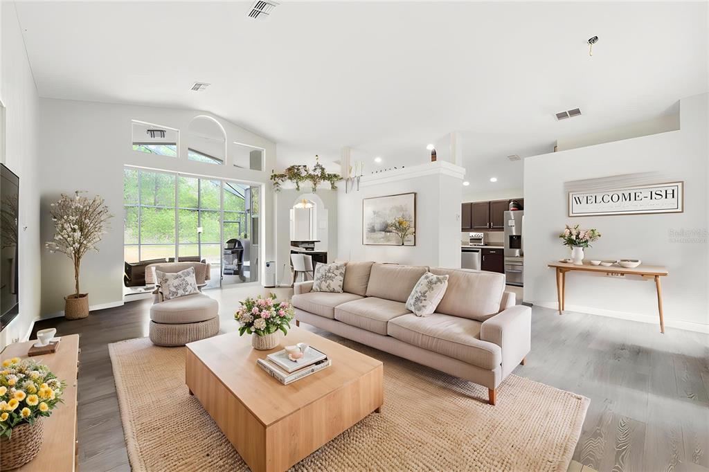 A bright living room features a beige sofa, wooden coffee table, and large glass doors — 11459 TRAIL RIDGE RUN, BROOKSVILLE, FL