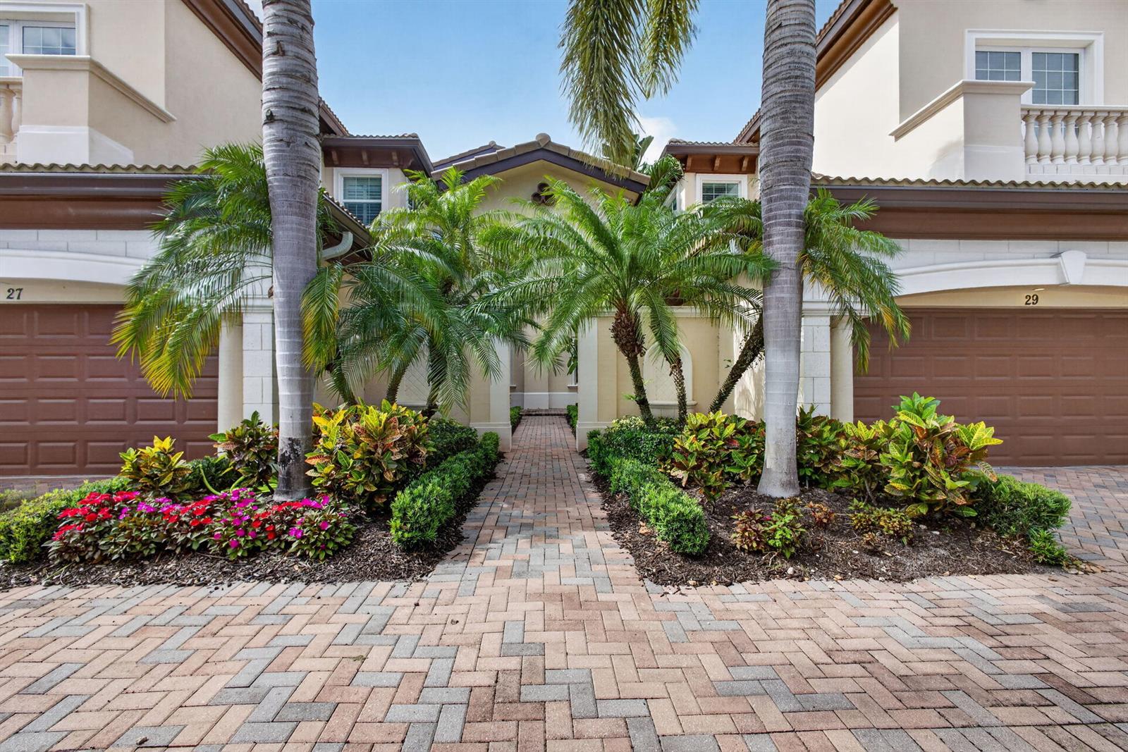 A paved walkway leads to the entrance between two townhomes with palm trees and landscaping — 111 Tresana Boulevard # 29, Jupiter FL 33478, JUPITER, FL