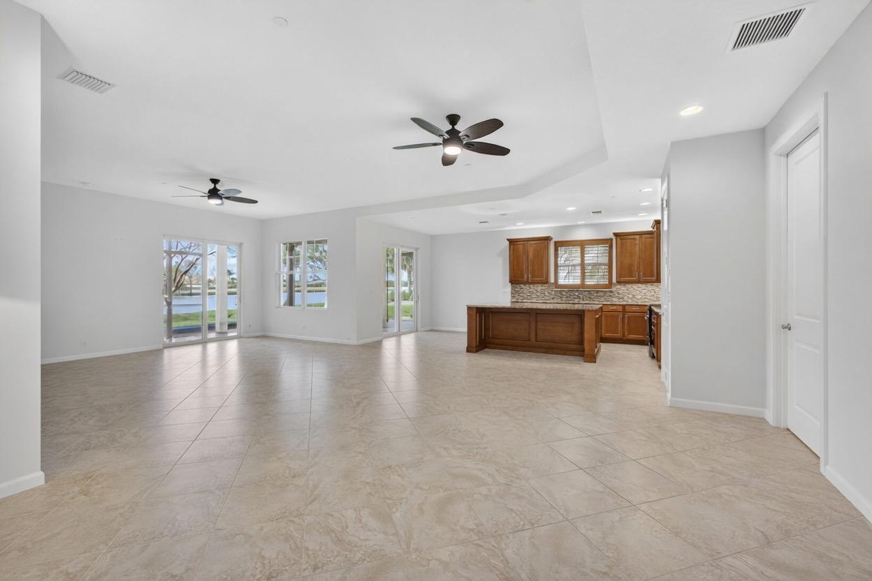 An open-concept living area features tile flooring, a kitchen with wood cabinets, and ceiling fans — 111 Tresana Boulevard # 29, Jupiter FL 33478, JUPITER, FL