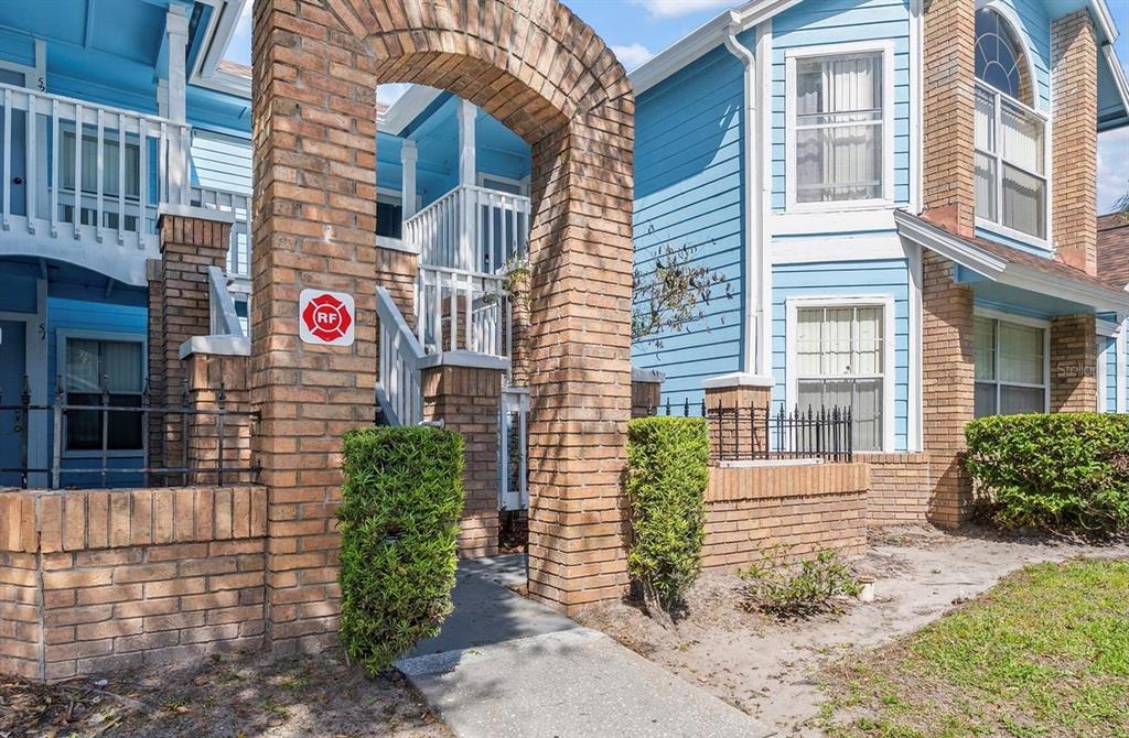 A brick archway leads to the entrance of a blue two-story apartment building — 2741 N POINCIANA BOULEVARD UNIT 49, KISSIMMEE, FL