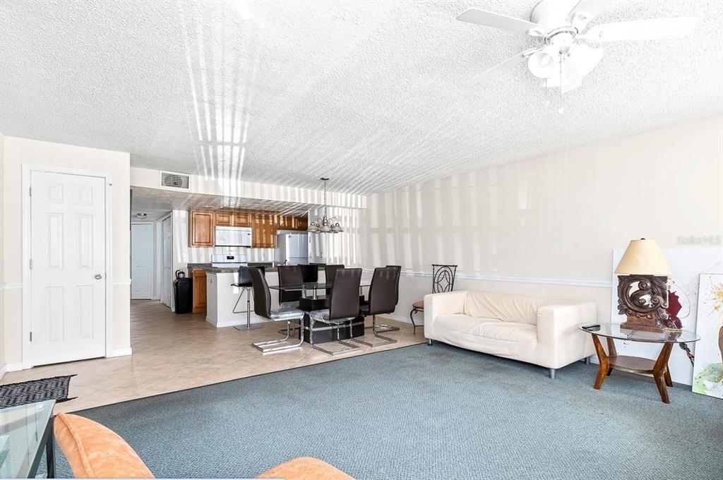 A living room with carpeted floors, a white sofa, and an adjacent kitchen with dining area — 2741 N POINCIANA BOULEVARD UNIT 49, KISSIMMEE, FL
