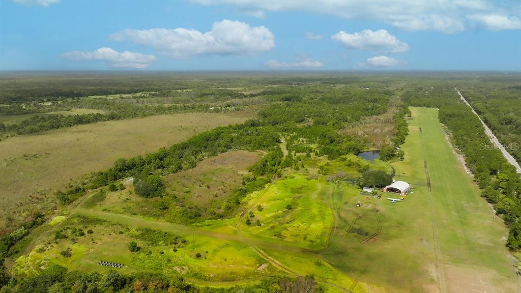 An aerial view shows a large grassy field with a hangar and a private airstrip — 520 HIGHLANDER DRIVE Lot 3, OAK HILL, FL