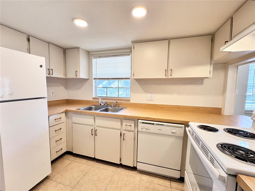 A kitchen features white cabinets, laminate countertops, a white refrigerator, and a white dishwasher — 1000 S SEMORAN BOULEVARD UNIT 305, WINTER PARK, FL