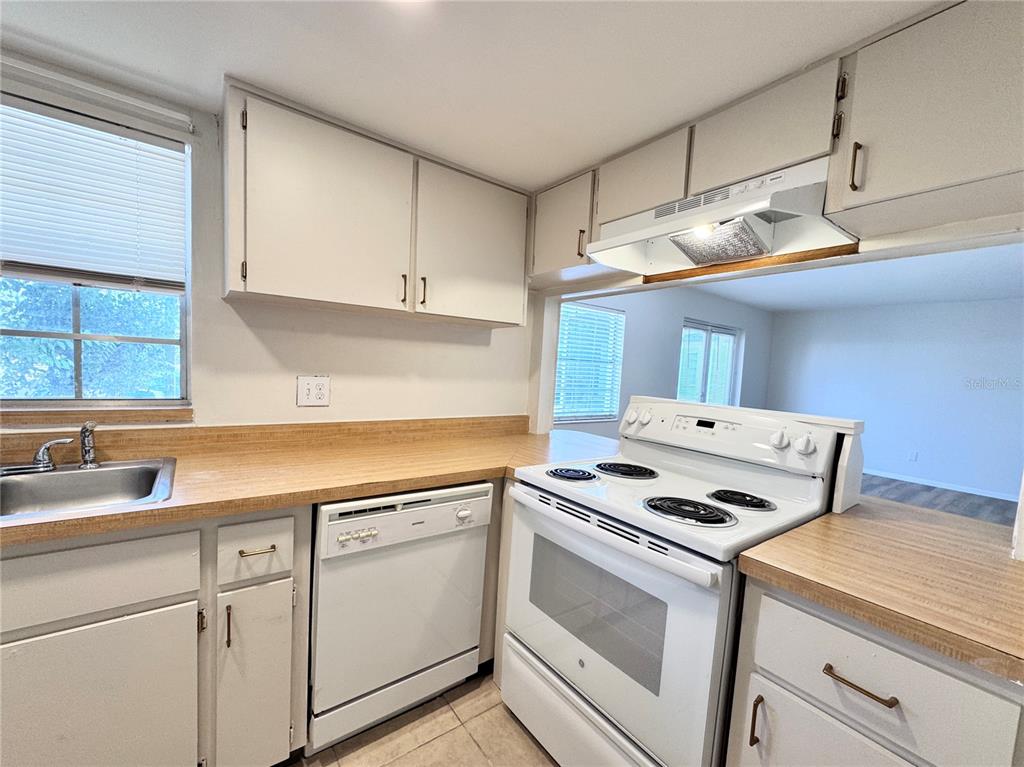 A kitchen features white cabinets, a laminate countertop, a white dishwasher, and a white stove — 1000 S SEMORAN BOULEVARD UNIT 305, WINTER PARK, FL
