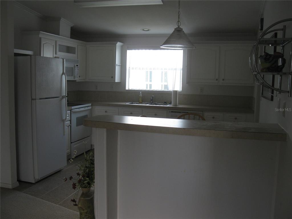 A kitchen features white cabinets, a white refrigerator, a stove, and a breakfast bar — 242 RAMSGATE WAY, HAINES CITY, FL
