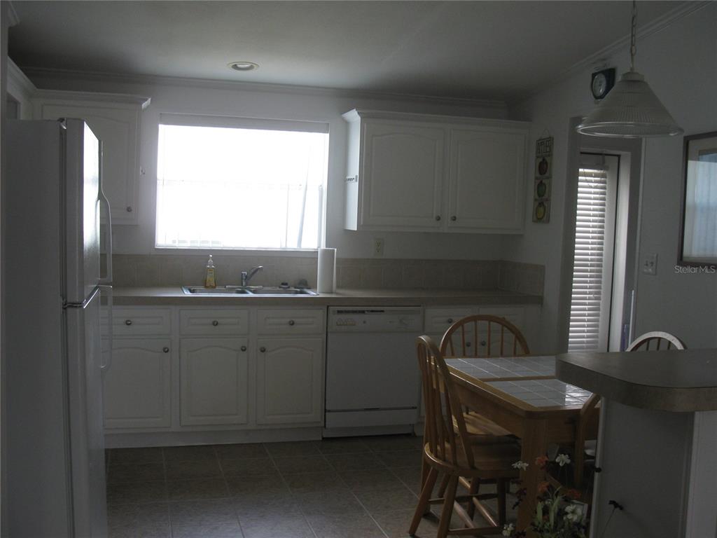 A kitchen features white cabinets, a double sink, a dishwasher, and a small dining table — 242 RAMSGATE WAY, HAINES CITY, FL
