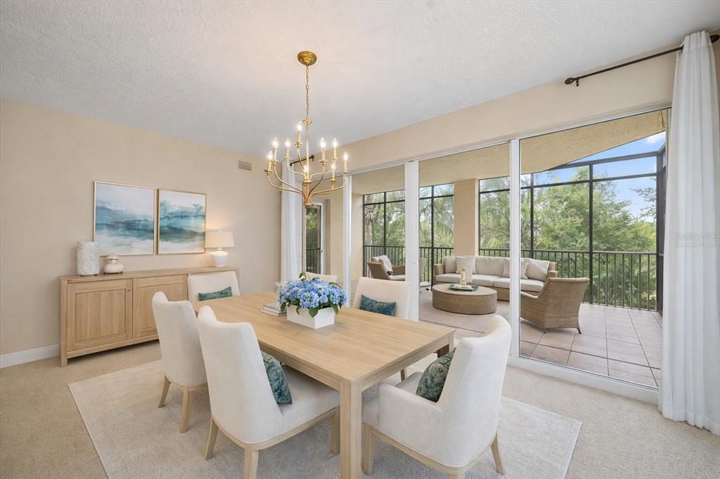 A dining room with a wooden table, upholstered chairs, and a sliding door to a balcony — 6482 WATERCREST WAY UNIT 204, LAKEWOOD RANCH, FL