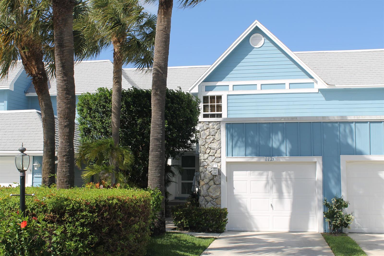 A light blue two-story townhouse with a stone facade and a white garage door — 1120 Ocean Dunes Circle, Jupiter FL 33477, JUPITER, FL