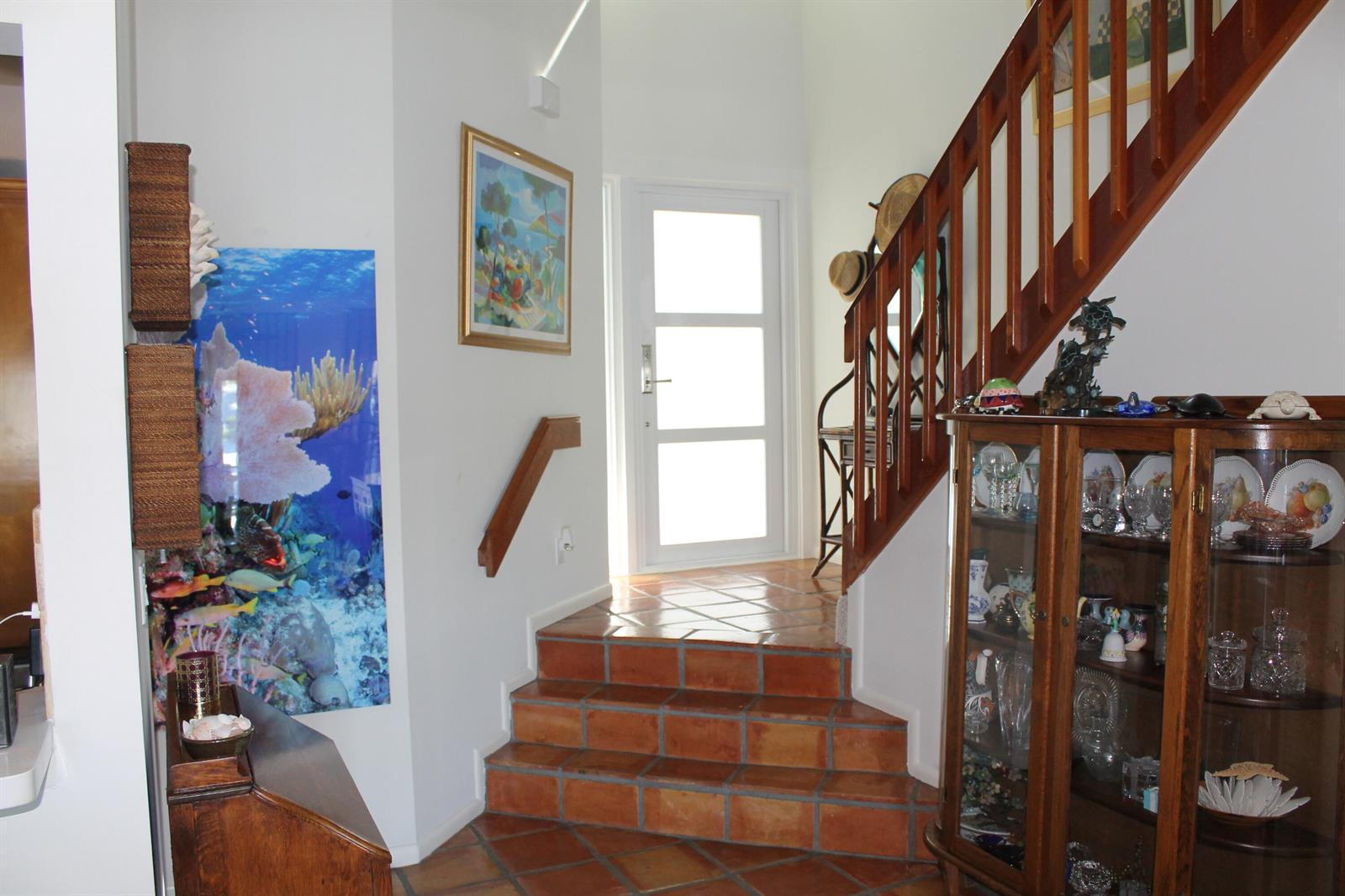 An entryway features terracotta tile stairs, a wooden staircase, and a glass-fronted display cabinet — 1120 Ocean Dunes Circle, Jupiter FL 33477, JUPITER, FL
