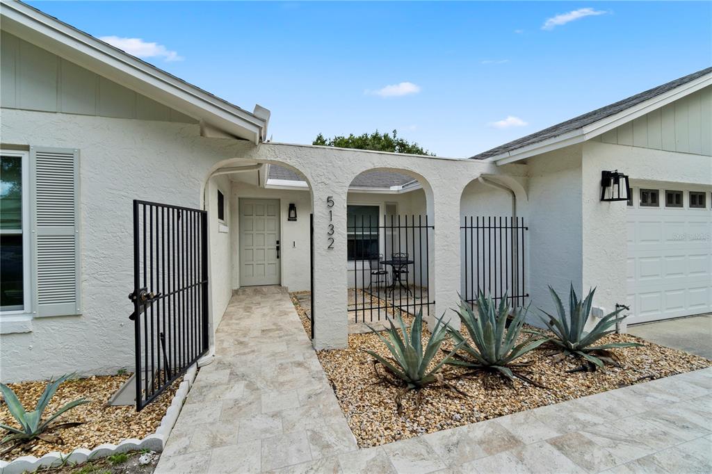 The exterior view shows a house entrance with a stone walkway, arched portico, and landscaping — 5132 TELLSON PLACE, ORLANDO, FL
