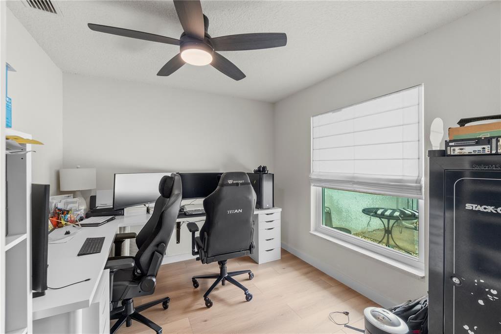 A home office features a white L-shaped desk, two gaming chairs, and a large gun safe — 5132 TELLSON PLACE, ORLANDO, FL