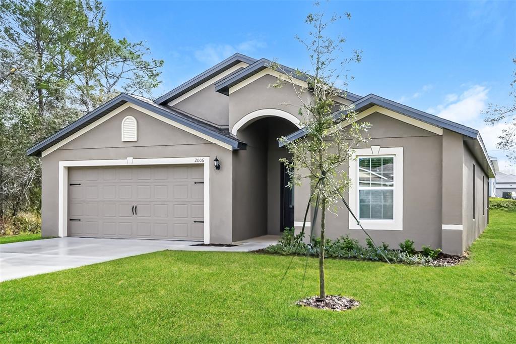 A single-story house with a gray stucco exterior, a two-car garage, and a front lawn — 2006 MAPLE LANE, KISSIMMEE, FL