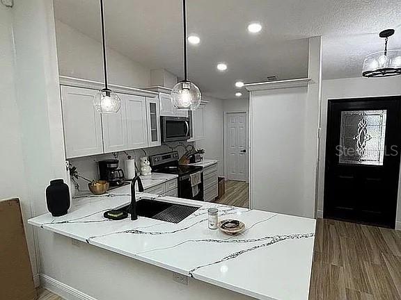 A kitchen features white cabinets, a quartz island countertop, and two pendant lights — 1423A OAK PLACE, APOPKA, FL