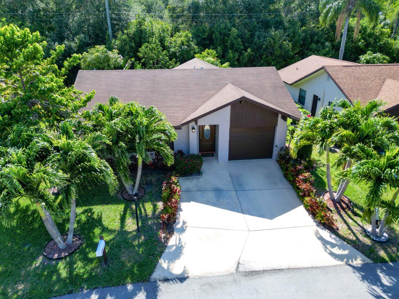 An aerial view of a single-story house with a brown roof, garage, and palm trees — 6345 Tall Cypress Circle, FL 33463, FL
