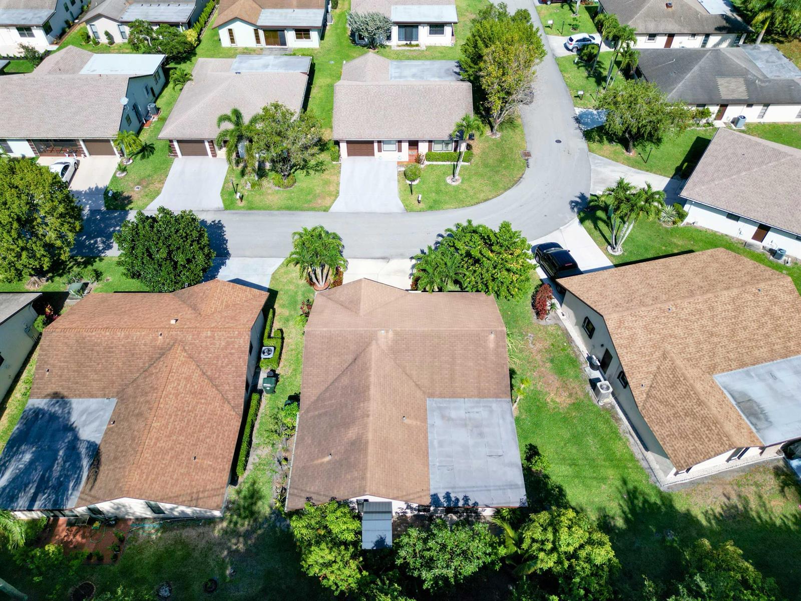 An aerial view shows several suburban houses with brown roofs and driveways on a street — 6345 Tall Cypress Circle, FL 33463, FL