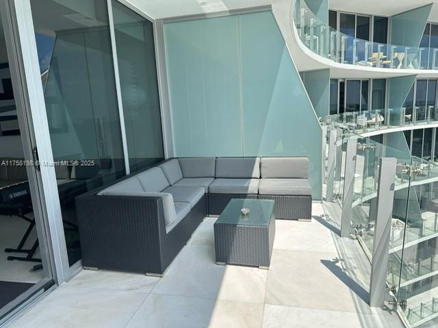 A balcony features a gray sectional sofa, a matching coffee table, and glass railings — 1 Collins Ave # 602, Miami Beach FL 33139, MIAMI BEACH, FL