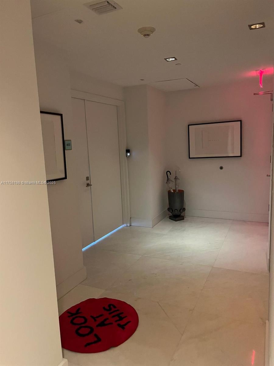 A bright entryway features light-colored tile floors, a white door, and a red circular rug — 1 Collins Ave # 602, Miami Beach FL 33139, MIAMI BEACH, FL
