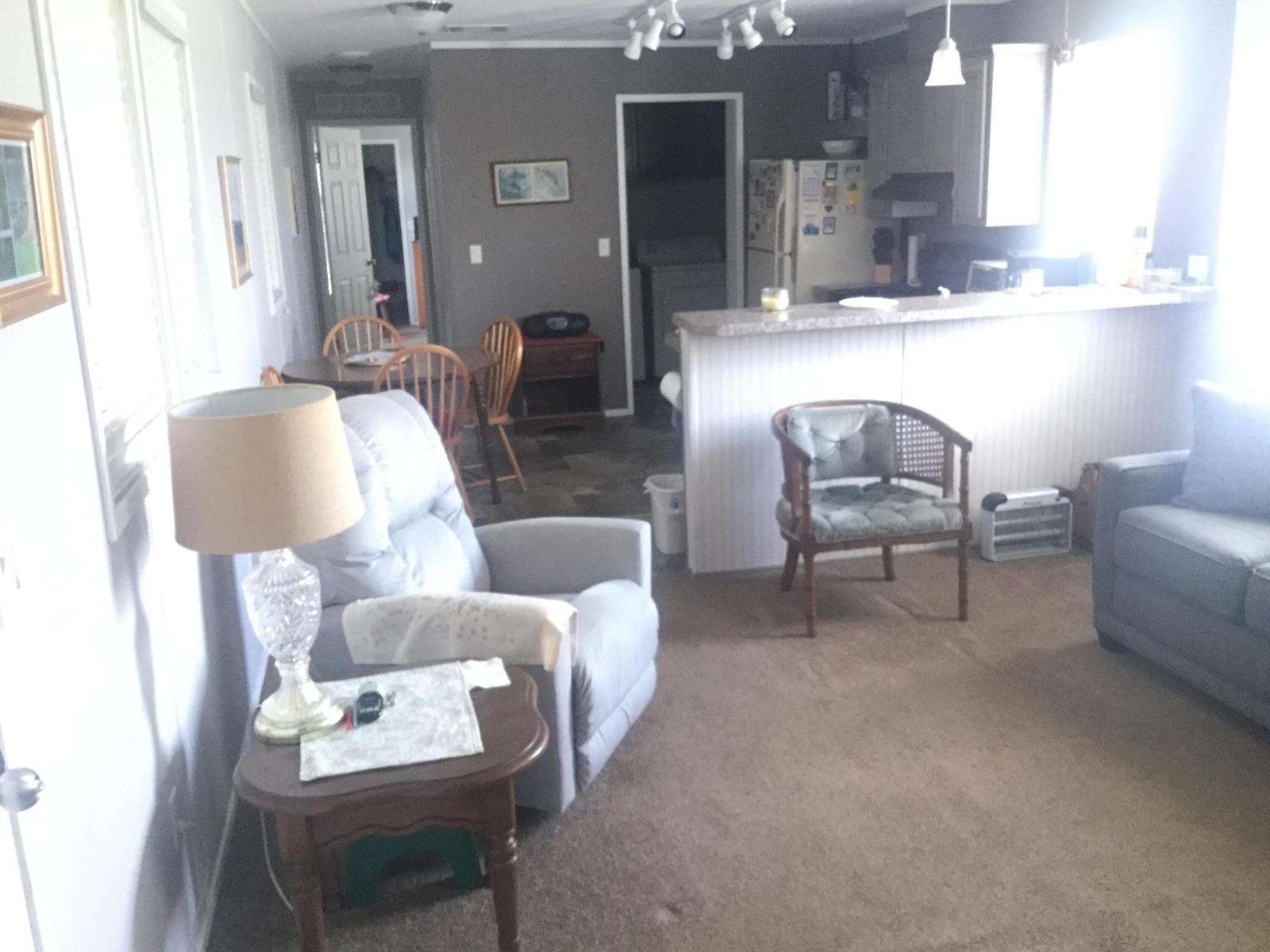 A living room with a recliner and lamp leads into a kitchen with a breakfast bar — 1753 West Avenue, Moore Haven FL 33471, MOORE HAVEN, FL