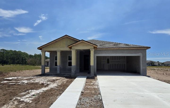 A single-story house under construction with a concrete driveway, stucco exterior, and covered front porch — 1623 CANE BAMBOO DRIVE, ST CLOUD, FL