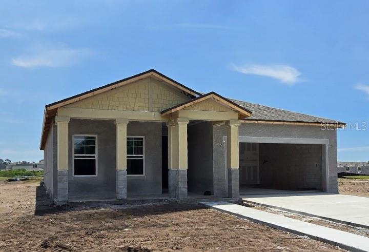 A single-story house under construction features a stucco exterior, stone-base columns, and an attached garage — 1623 CANE BAMBOO DRIVE, ST CLOUD, FL