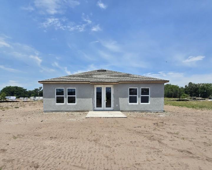 A single-story house with a gray stucco exterior, a tiled roof, and double front doors — 1623 CANE BAMBOO DRIVE, ST CLOUD, FL