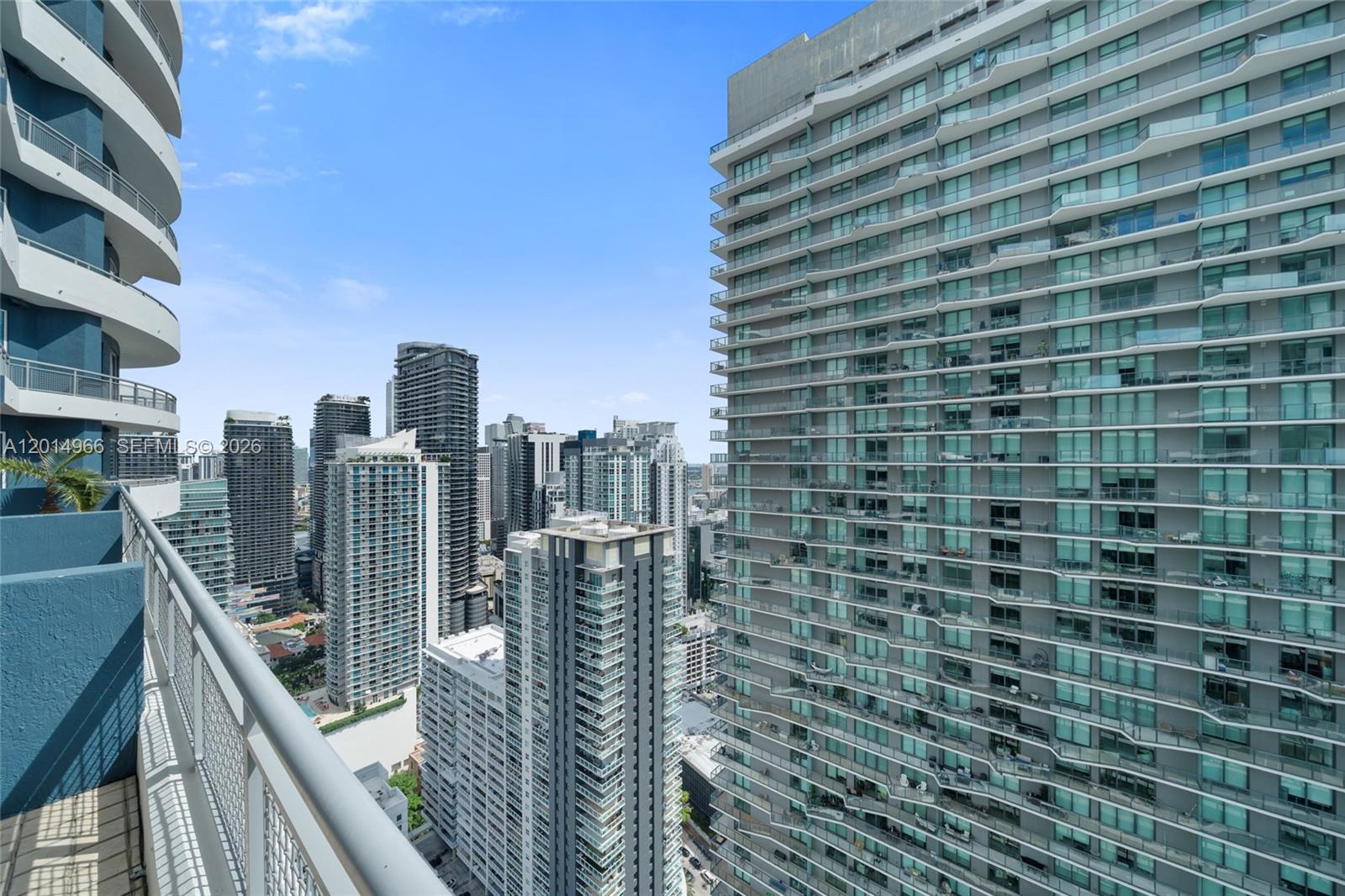A high-angle view from a balcony overlooking a dense urban skyline of modern skyscrapers — 60 SW 13th St # 4008, Miami FL 33130, MIAMI, FL