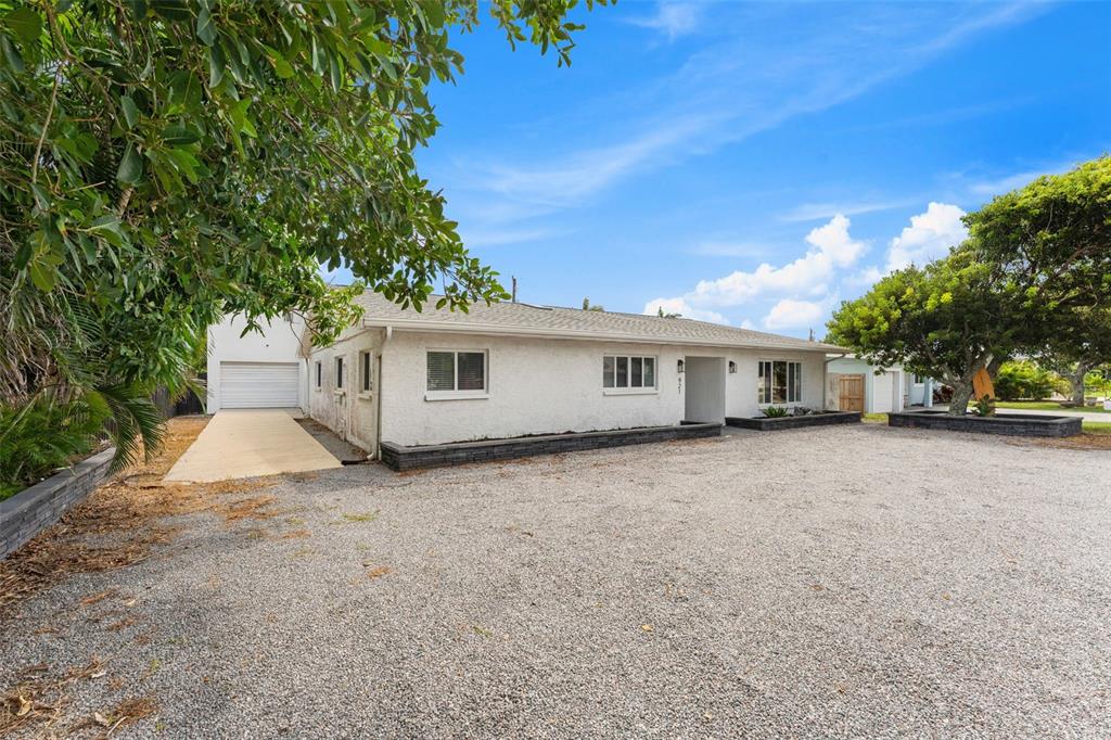 A single-story house with a white stucco exterior and a large gravel driveway — 921 S ORLANDO AVENUE, COCOA BEACH, FL
