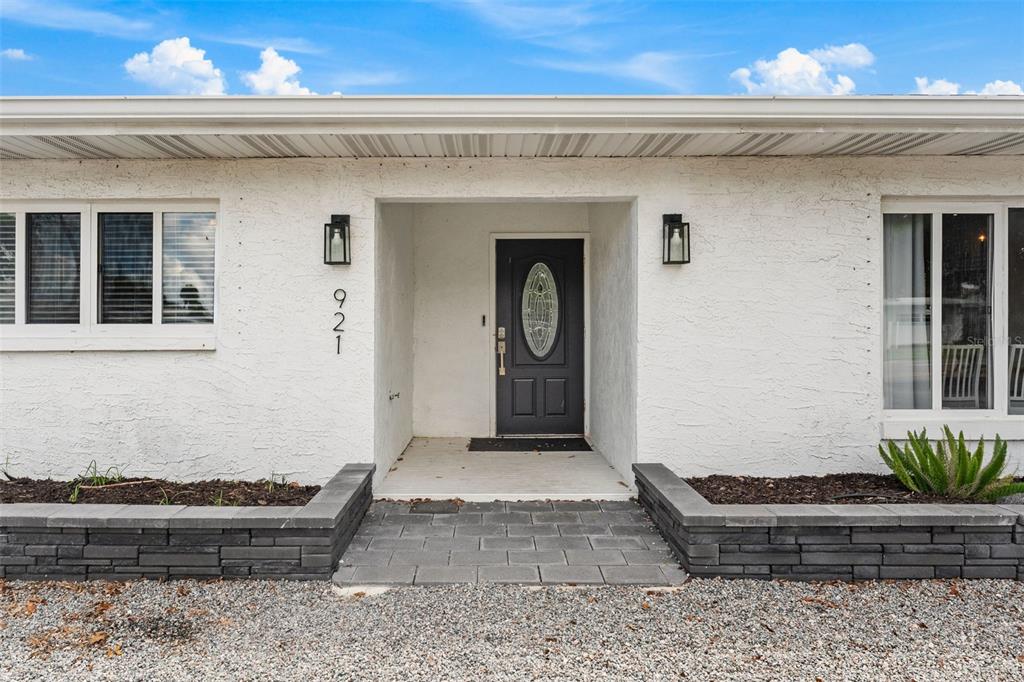 The exterior of a white house features a dark front door and stone-walled planters — 921 S ORLANDO AVENUE, COCOA BEACH, FL