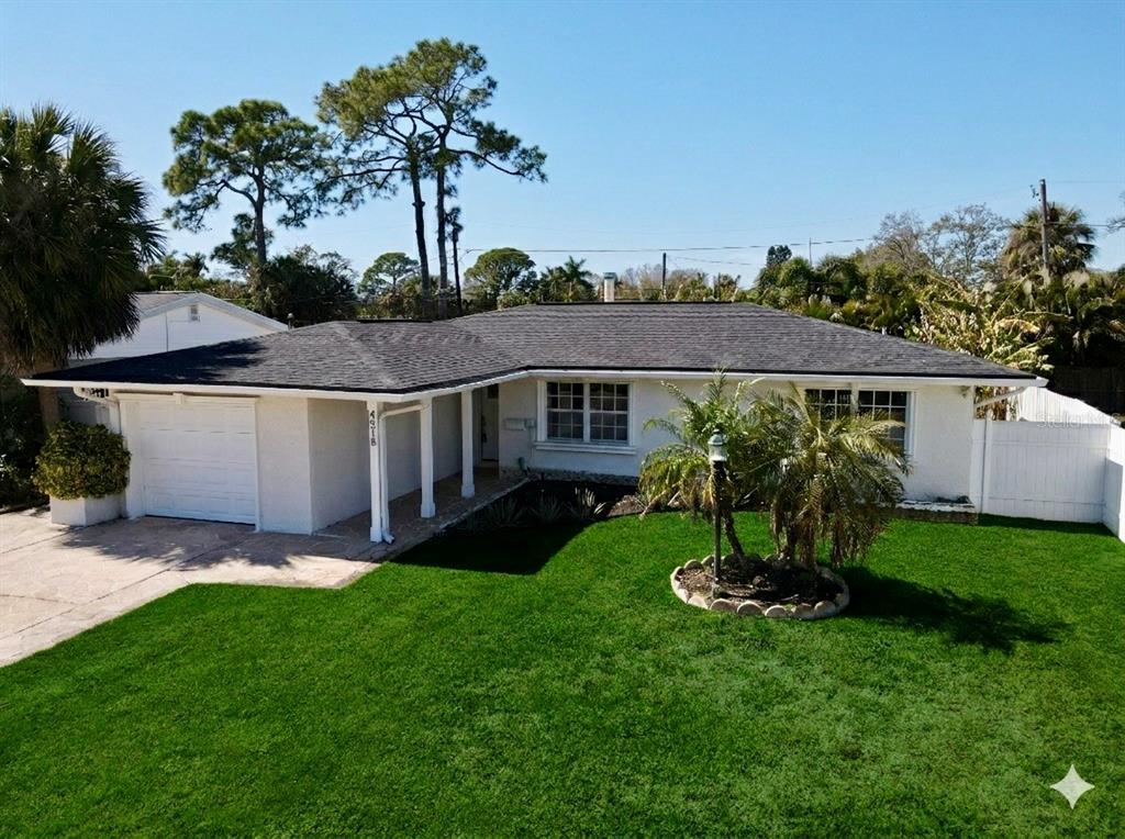 A single-story white house with a dark shingled roof and a green front lawn — 4518 HELENA STREET NE, ST PETERSBURG, FL