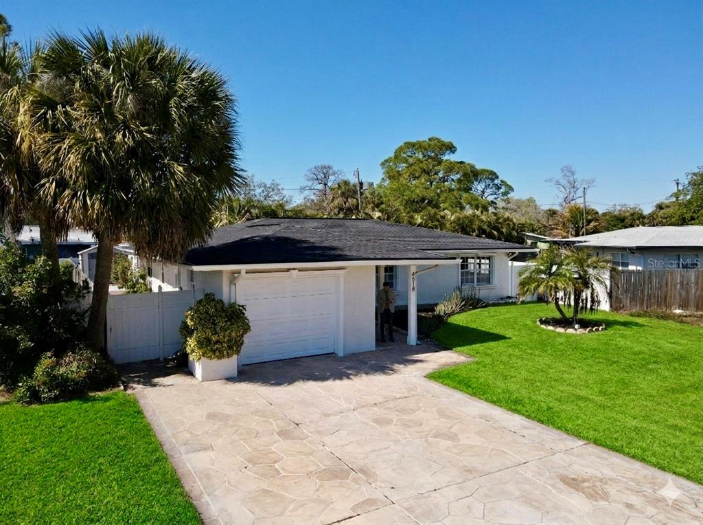 A single-story white house with a dark roof, a stone driveway, and a green lawn — 4518 HELENA STREET NE, ST PETERSBURG, FL