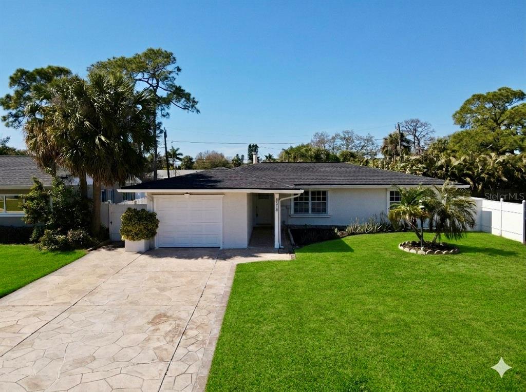 A single-story house with a white exterior, a dark roof, and a paved driveway — 4518 HELENA STREET NE, ST PETERSBURG, FL