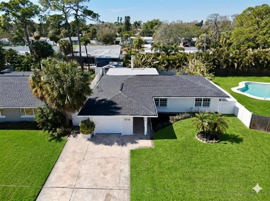 An aerial view of a single-story house with a dark shingled roof and pool — 4518 HELENA STREET NE, ST PETERSBURG, FL