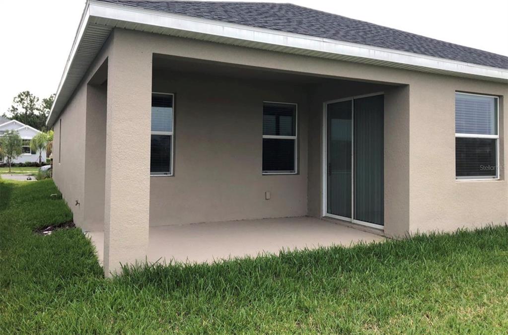 A covered concrete patio sits at the rear of a beige stucco house — 10229 LOVEGRASS LANE, ORLANDO, FL