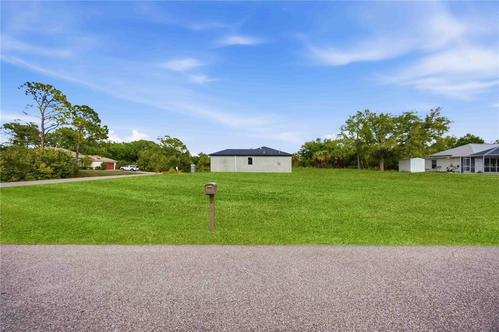 A vacant, grassy residential lot features a single mailbox and a neighboring house in back — ATTALLA AVENUE, NORTH PORT, FL