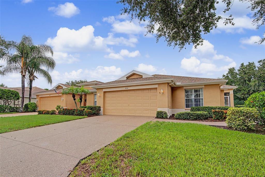 A single-story tan house with a two-car garage and a paved driveway — 2241 WORTHINGTON GREENS DRIVE, SUN CITY CENTER, FL
