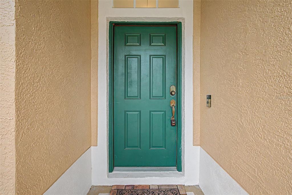 A green six-panel front door is set within a tan stucco entryway — 2241 WORTHINGTON GREENS DRIVE, SUN CITY CENTER, FL