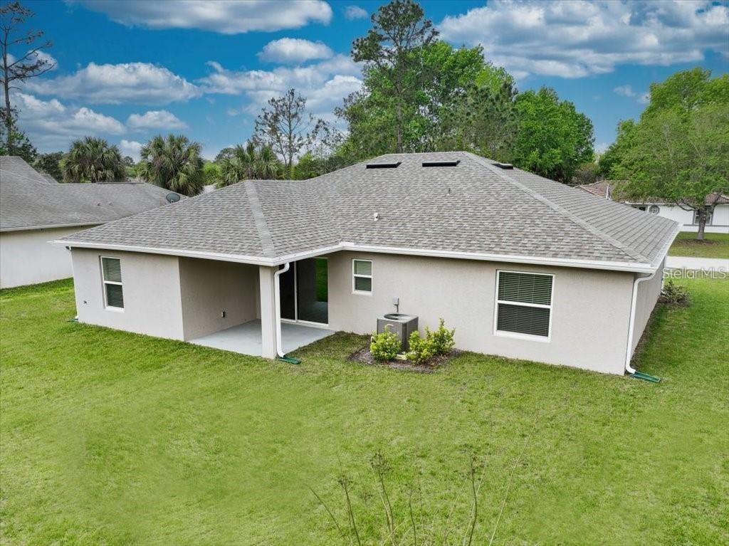 The rear exterior of a single-story house features a covered patio and a grassy yard — 14 POWDER LANE, PALM COAST, FL