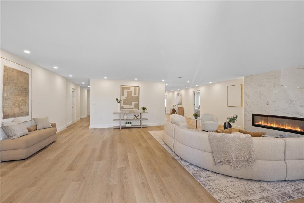 A spacious living room features light wood flooring, a curved sofa, and a marble fireplace — 4531 44TH STREET S, ST PETERSBURG, FL