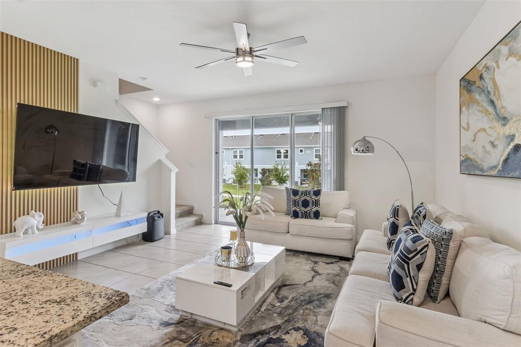 A living room features a white sofa, a coffee table, and a wall-mounted television — 1707 WOODEN STREET, DAVENPORT, FL