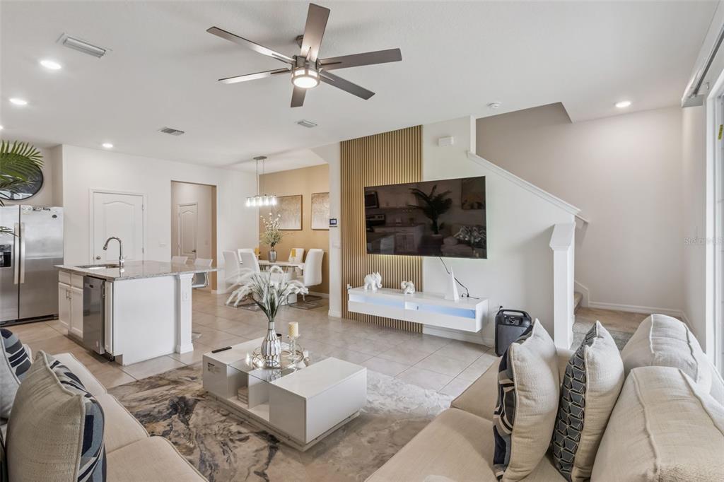 A modern living room features a wall-mounted television, a slatted wood accent wall, and an open-concept kitchen — 1707 WOODEN STREET, DAVENPORT, FL