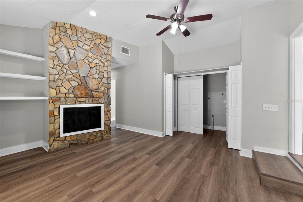 A living room features wood-look flooring, a stone fireplace, built-in shelves, and a ceiling fan — 1150 52ND STREET, SARASOTA, FL