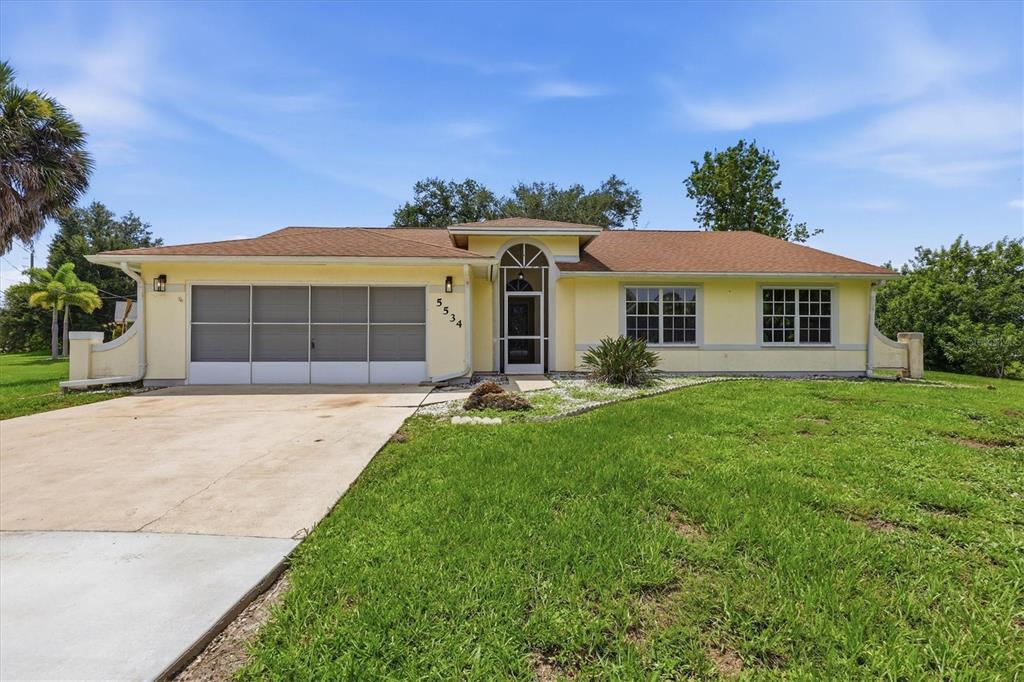 A single-story yellow house with a brown roof, a garage, and a front lawn — 5534 DAVID BOULEVARD, PORT CHARLOTTE, FL