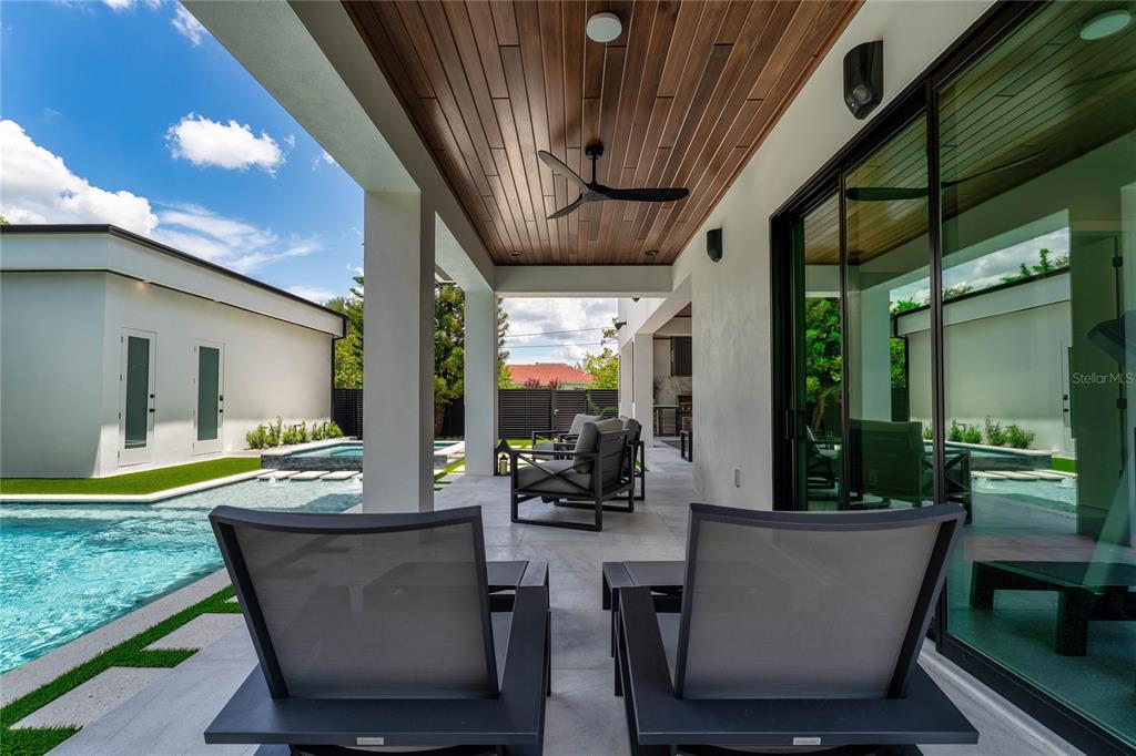 A covered patio features a wood-paneled ceiling, a ceiling fan, and views of a pool — 5002 W POE AVENUE, TAMPA, FL