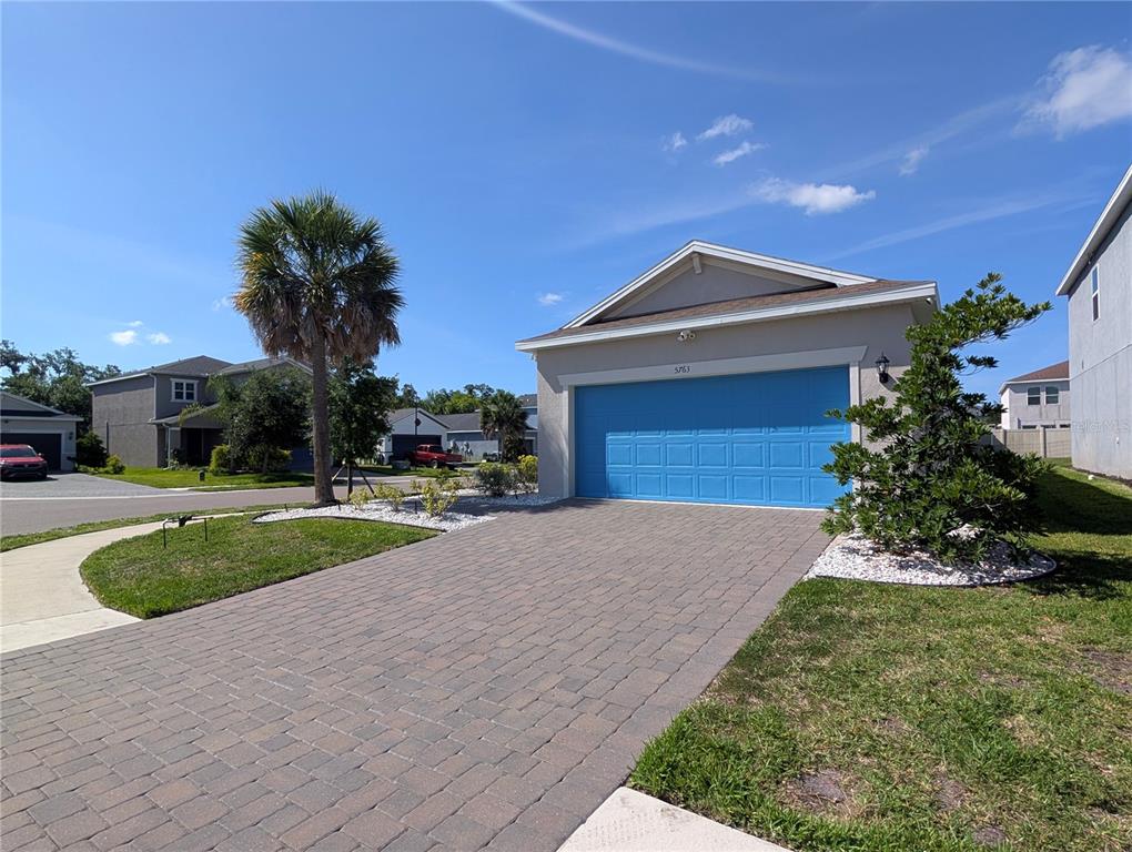 A single-story house with a blue garage door and a paved driveway under a blue sky — 5763 BUNGALOW GROVE COURT, PALMETTO, FL