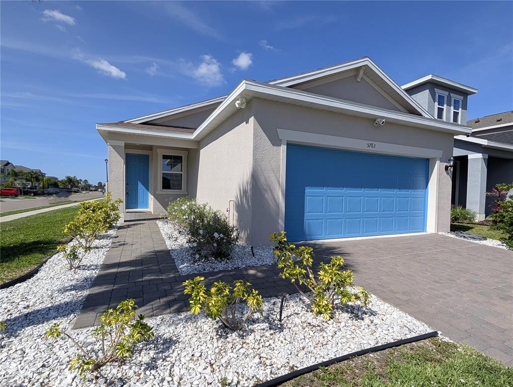 A single-story house with a blue garage door, blue front door, and white rock landscaping — 5763 BUNGALOW GROVE COURT, PALMETTO, FL