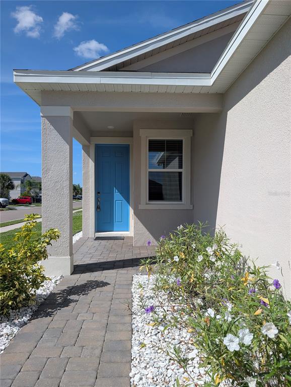 A paved walkway leads to a covered entryway with a bright blue front door — 5763 BUNGALOW GROVE COURT, PALMETTO, FL