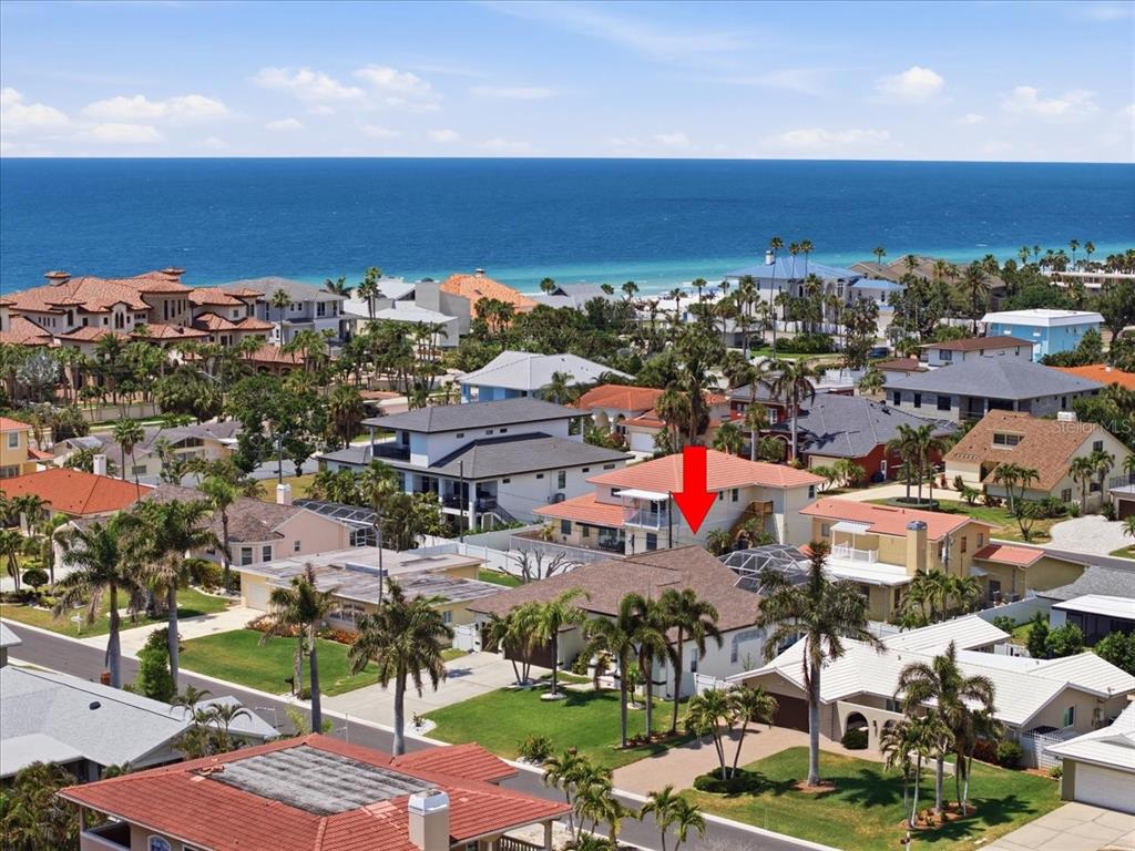 An aerial view shows a coastal neighborhood with houses, palm trees, and the ocean beyond — 109 16TH STREET, BELLEAIR BEACH, FL