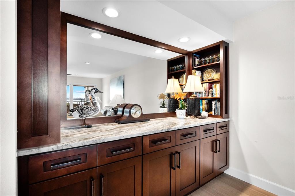 A built-in wet bar features dark wood cabinetry, a marble countertop, and a large mirror — 71 TIDY ISLAND BOULEVARD, BRADENTON, FL