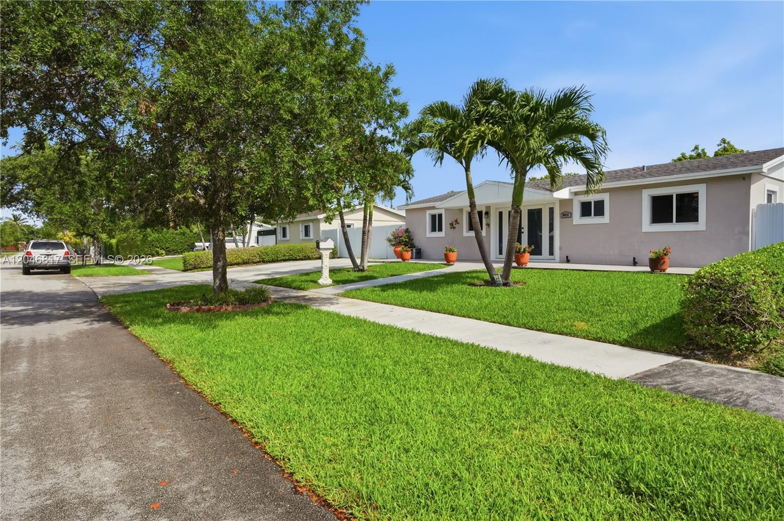 A single-story house with a light-colored exterior, a manicured lawn, and two palm trees — 10451 SW 201st Ter, Cutler Bay FL 33189, CUTLER BAY, FL