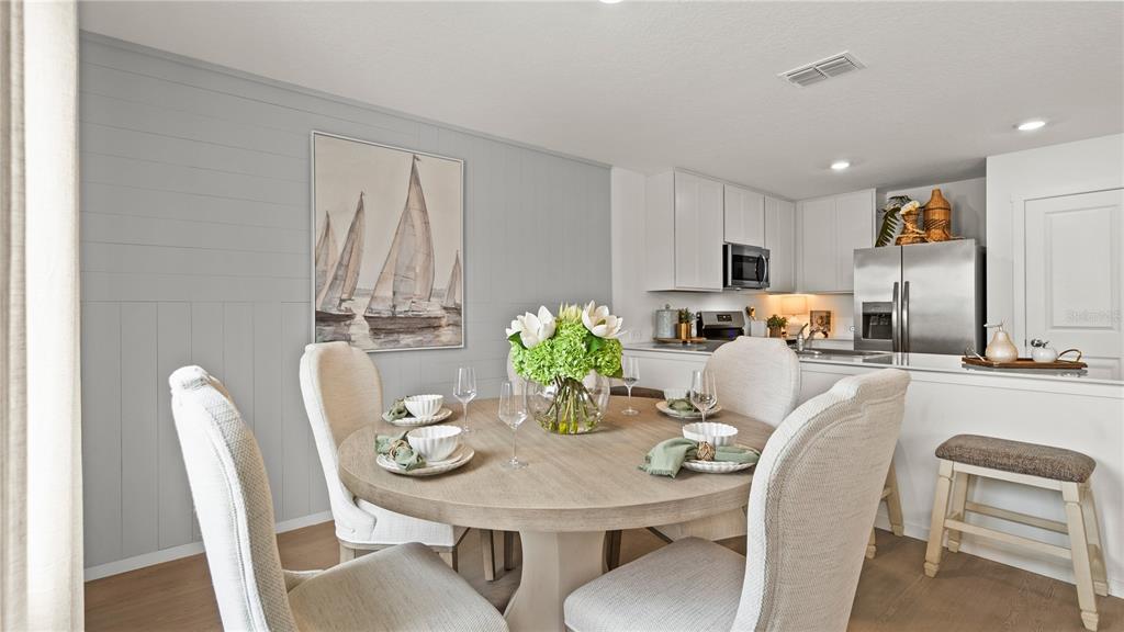 A dining area with a round wooden table and chairs sits next to a kitchen — 559 ARTEMIS STREET, LAKE WALES, FL